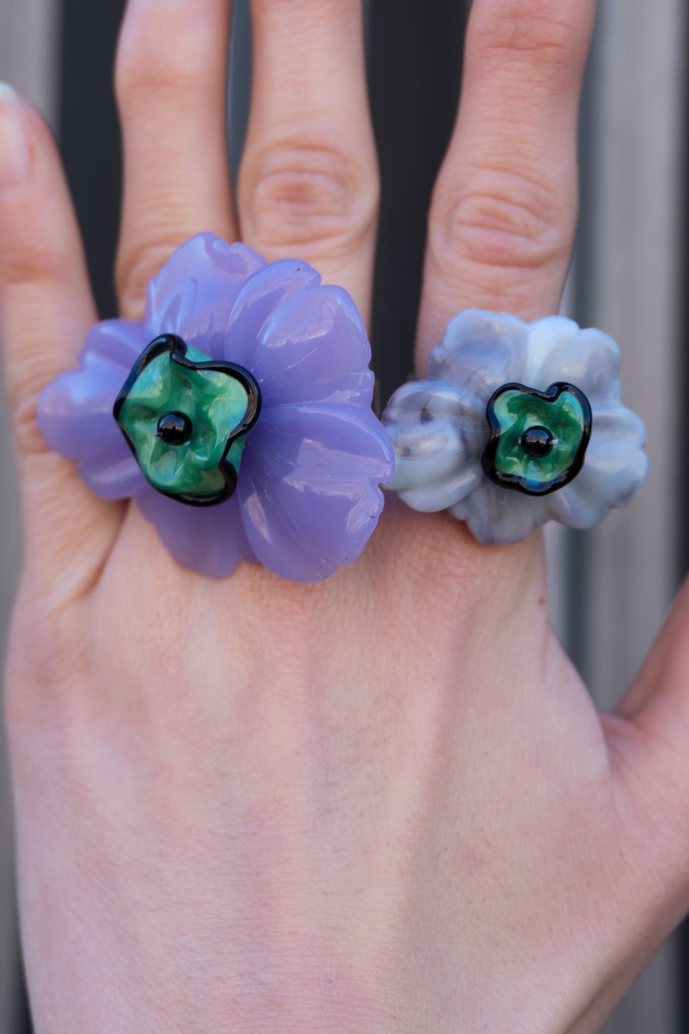 Anillo bordado violeta con diseño floral, flor de vidrio checo y flor de resina vintage, en mano de modelo, marca Uchaworld.