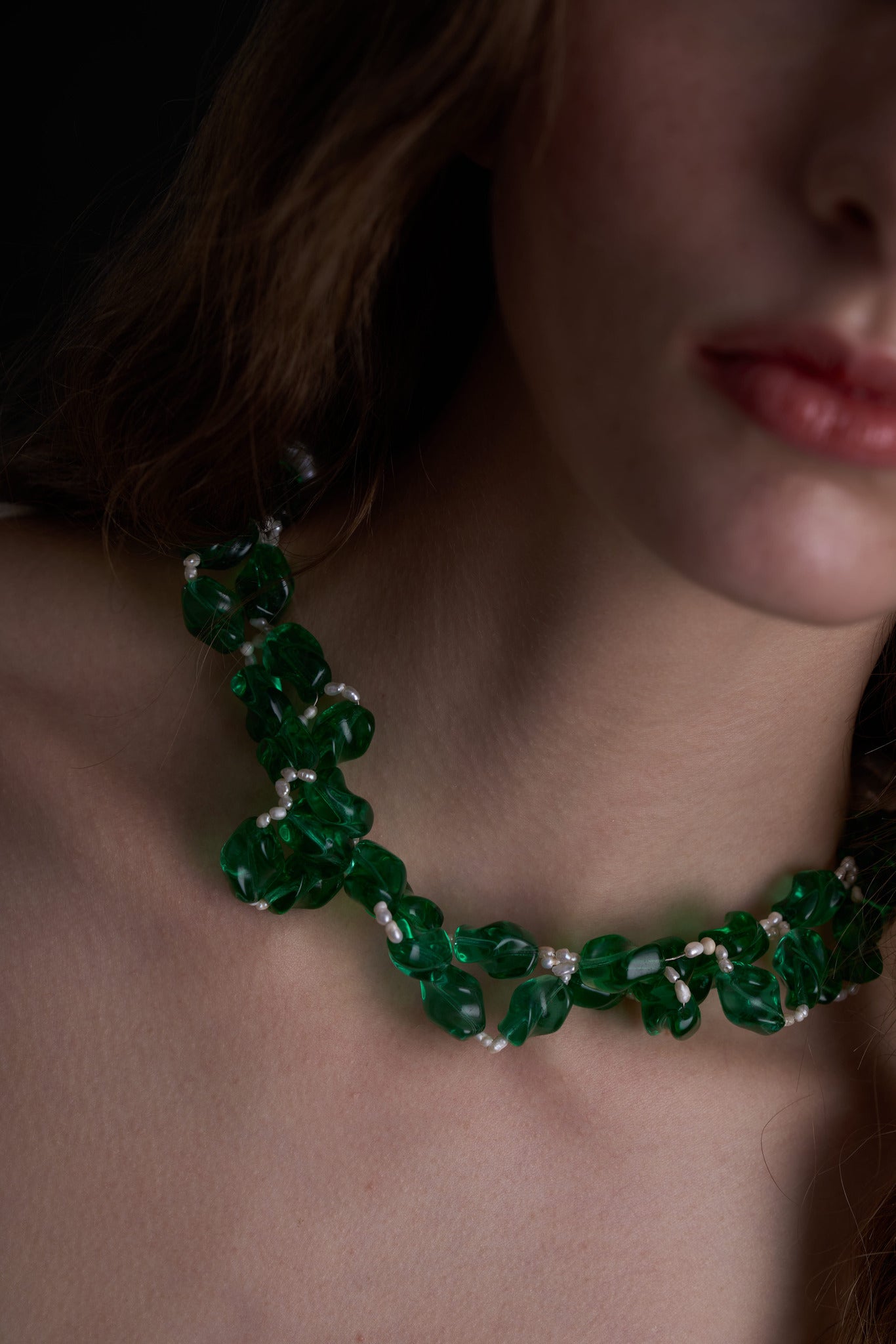 Collar artesanal con diseño retorcido con un elegante tono verde esmeralda y perlas, en modelo, marca Uchaworld.