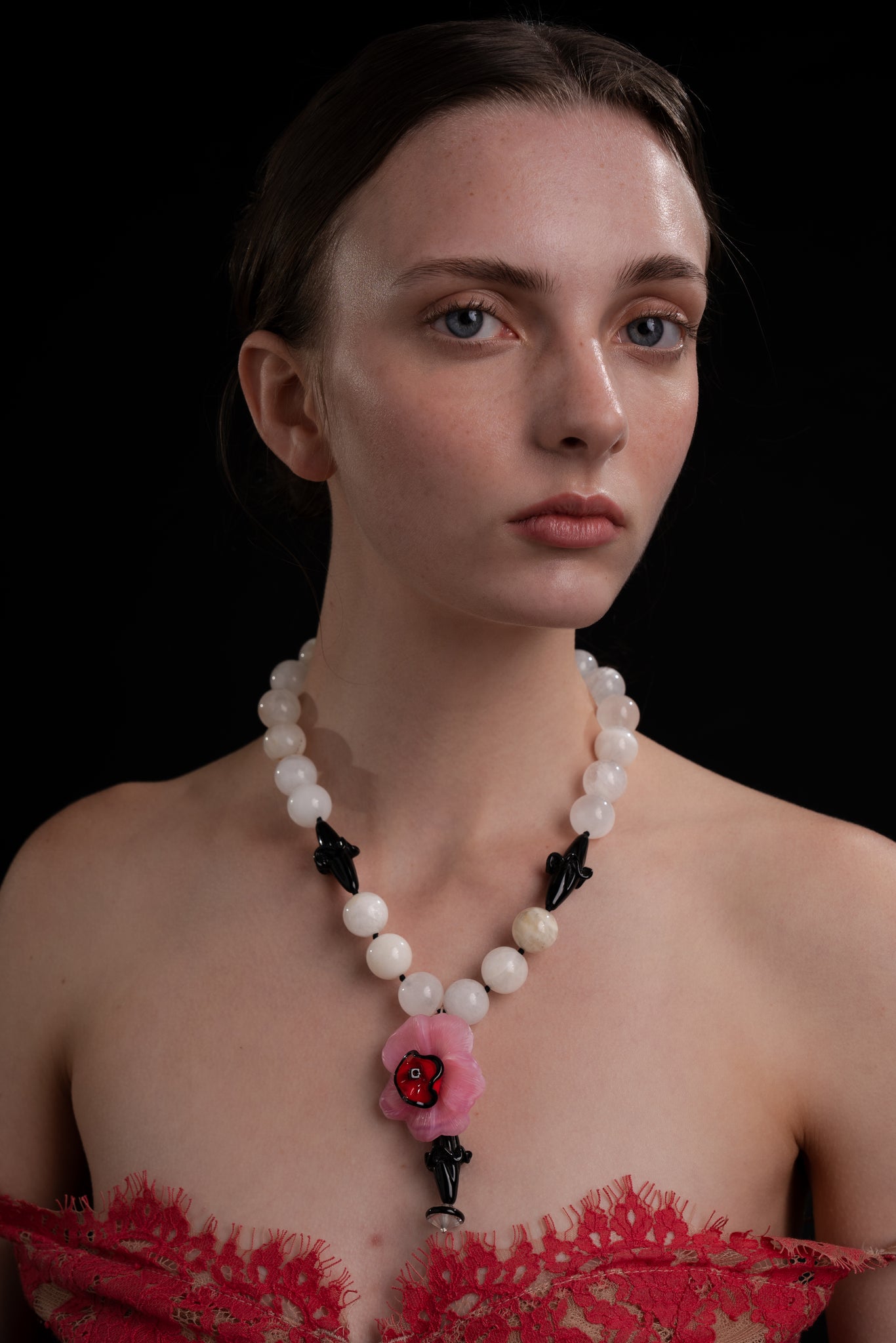 Collar artesanal con cuentas en tonos blanco & negro y colgante floral rosa, en modelo, marca Uchaworld.