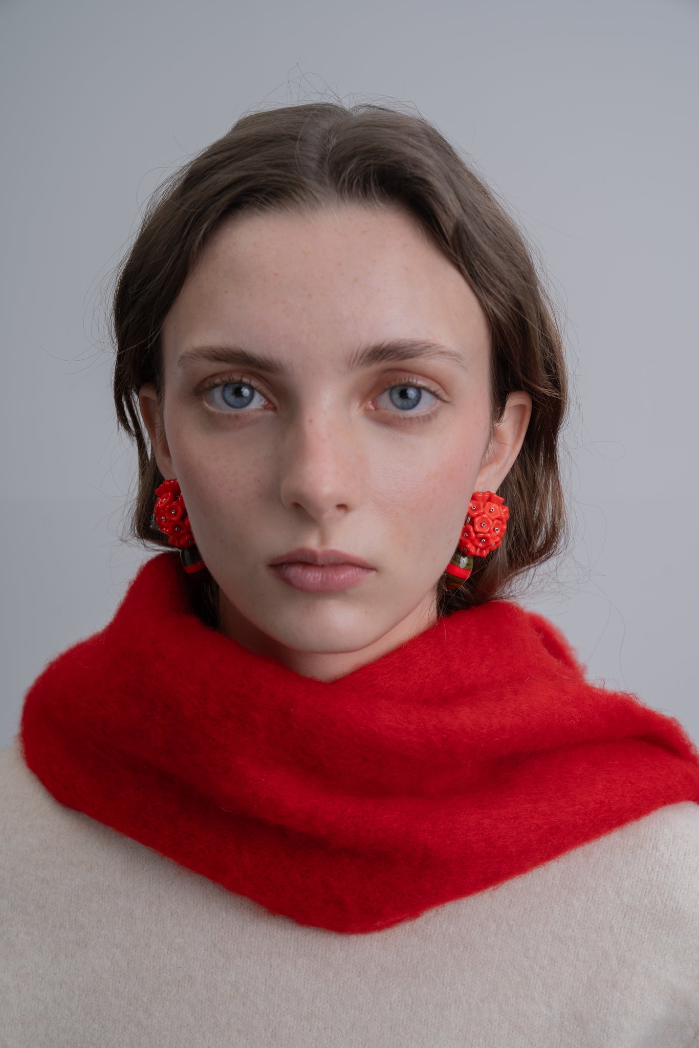 Pendientes en rojo bordados con flores de cristal de checo y cuenta de resina vintage, de Uchaworld, mostrados en modelo.
