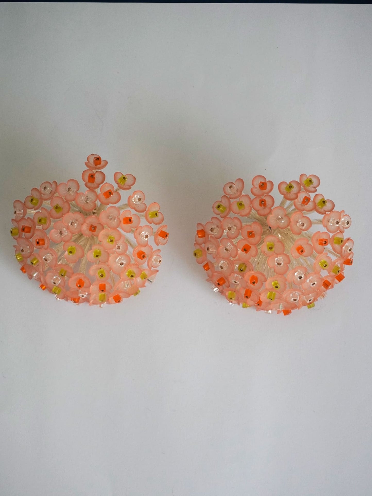 Pendientes bordados color rosa y multicolor, con diseño floral y cuentas de acrilico y cristal, fondo gris, marca Uchaworld.