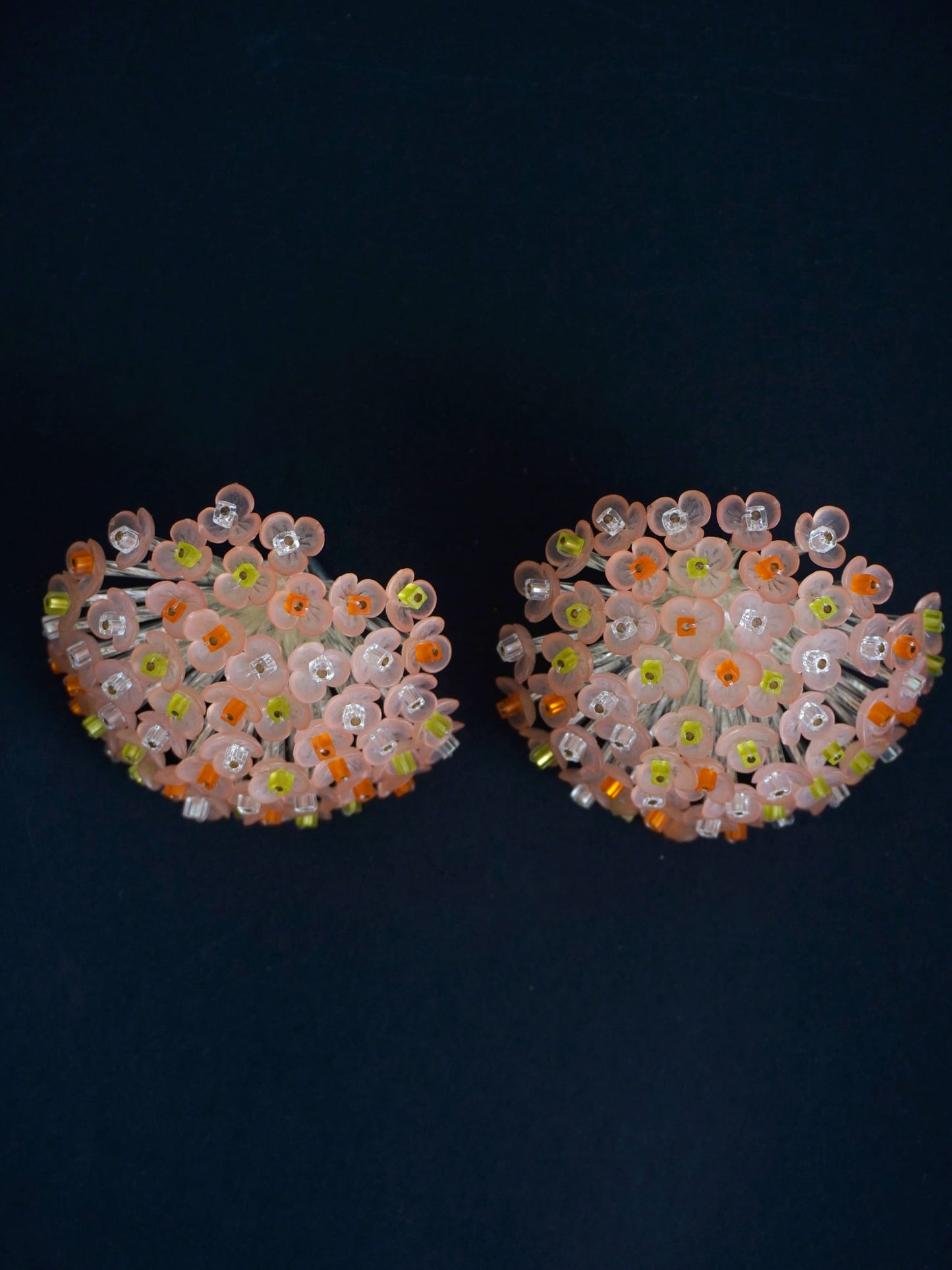 Pendientes bordados color rosa y multicolor, con diseño floral y cuentas de acrilico y cristal, fondo negro, marca Uchaworld.