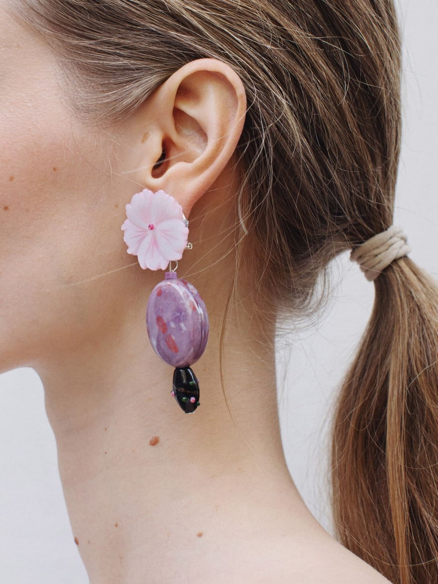 Pendientes bordados con flor de madreperla australiana y cuenta de vidrio africana, en modelo, marca Uchaworld.
