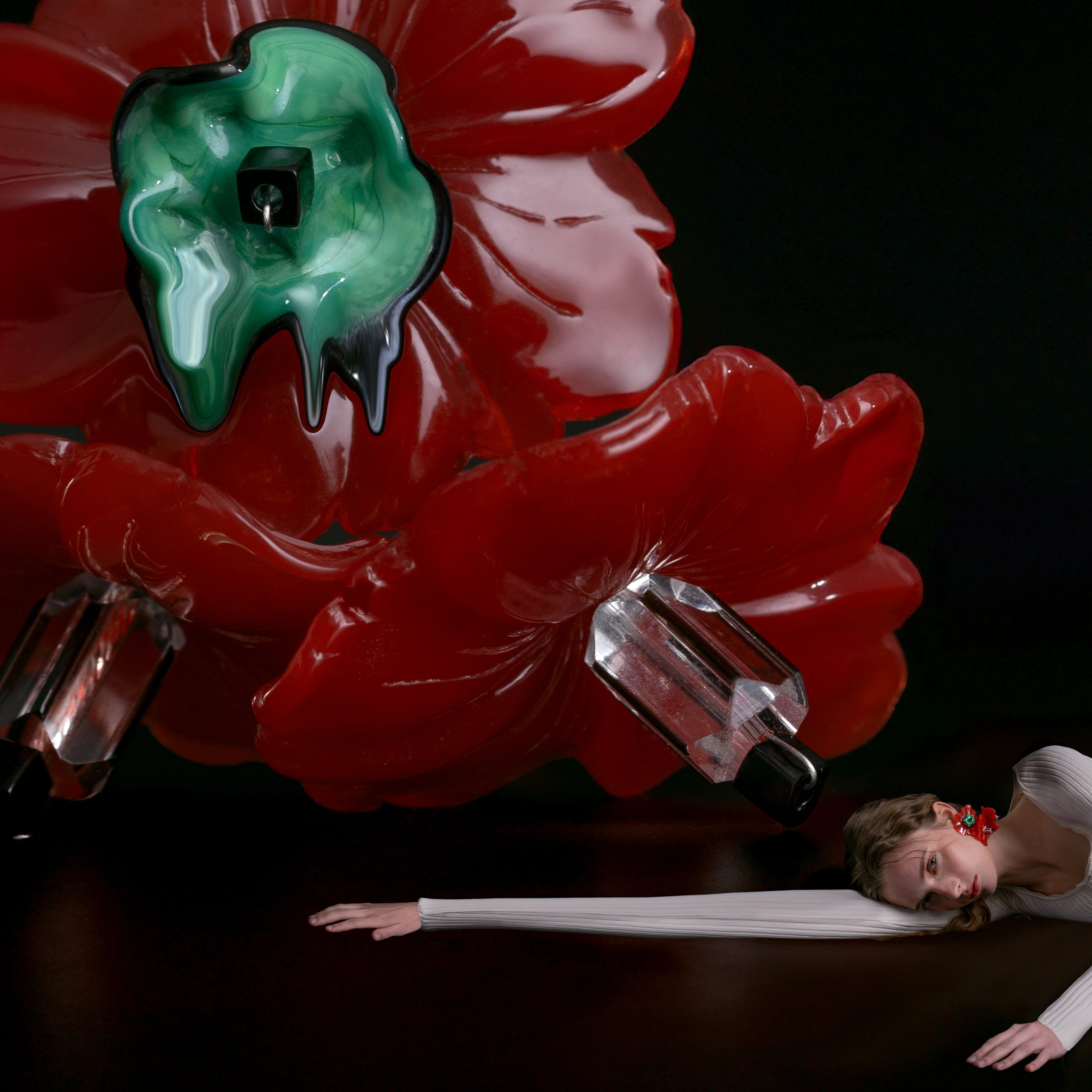 A model lies on the floor wearing a surreal earring.