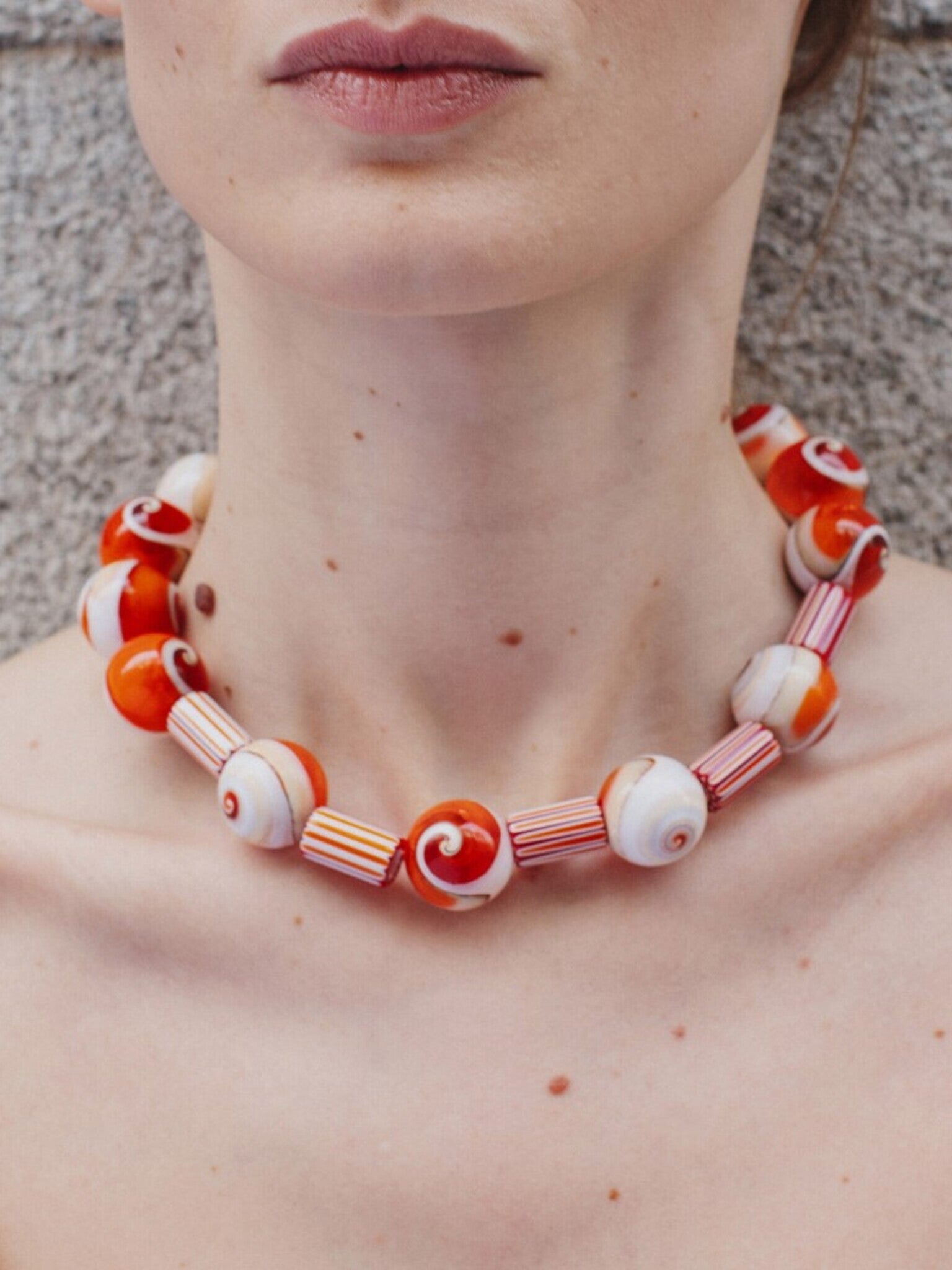 Collar artesanal con piedras de vidrio y cuentas de murano rayadas naranjas y blancas, en modelo, marca Uchaworld.