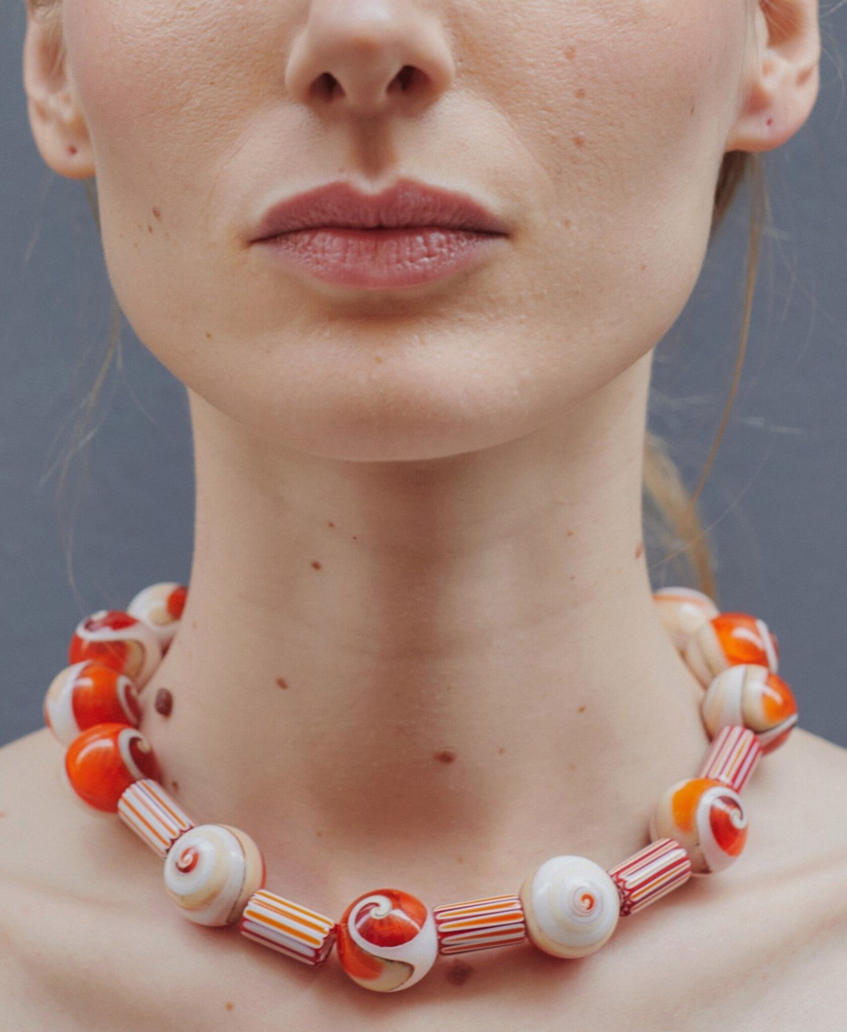 Collar artesanal con piedras de vidrio y cuentas de murano rayadas naranjas, en modelo, marca Uchaworld.