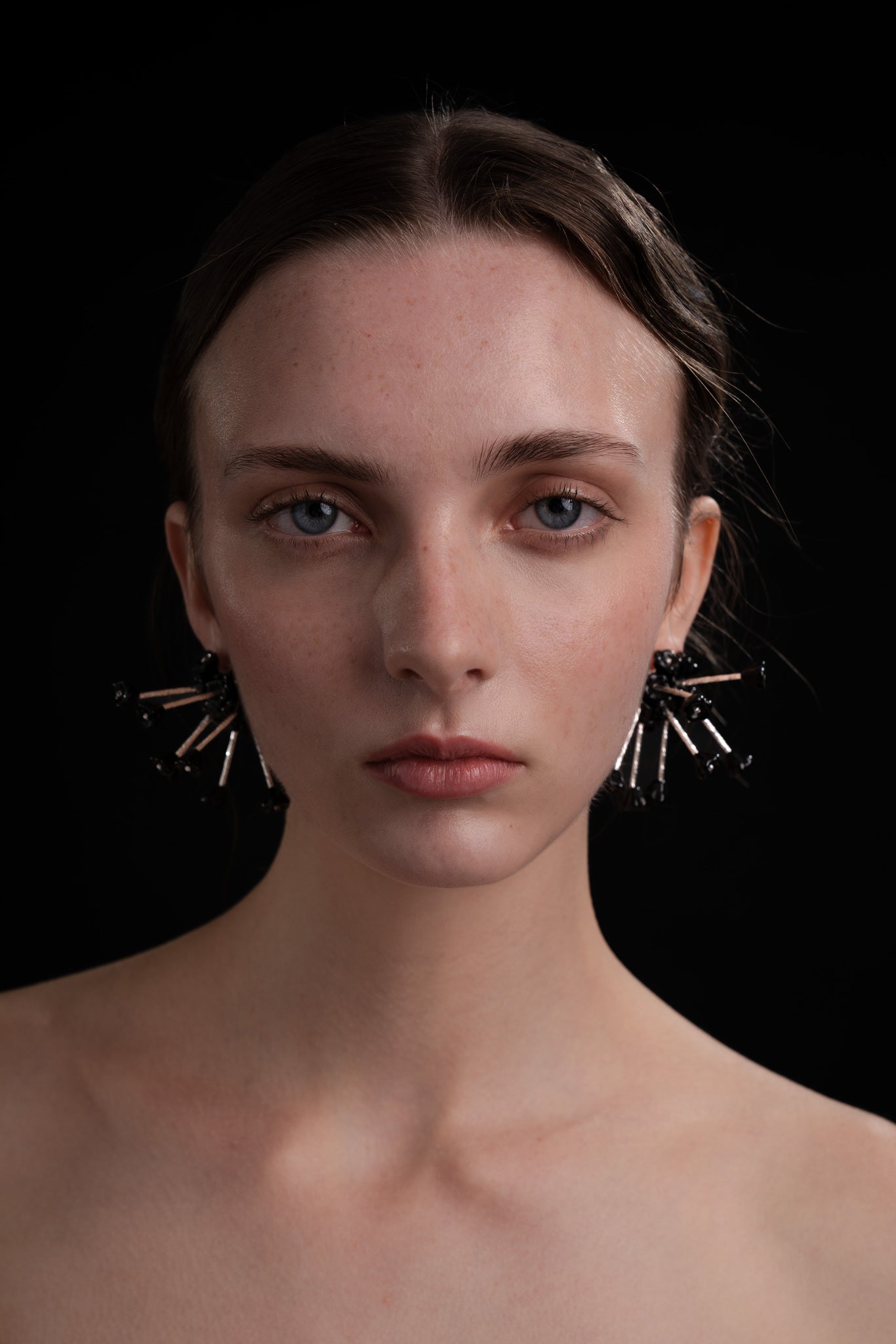 Pendientes en negro bordados con flores de cristal de checo y piezas de plata de ley, de Uchaworld, mostrados en modelo.