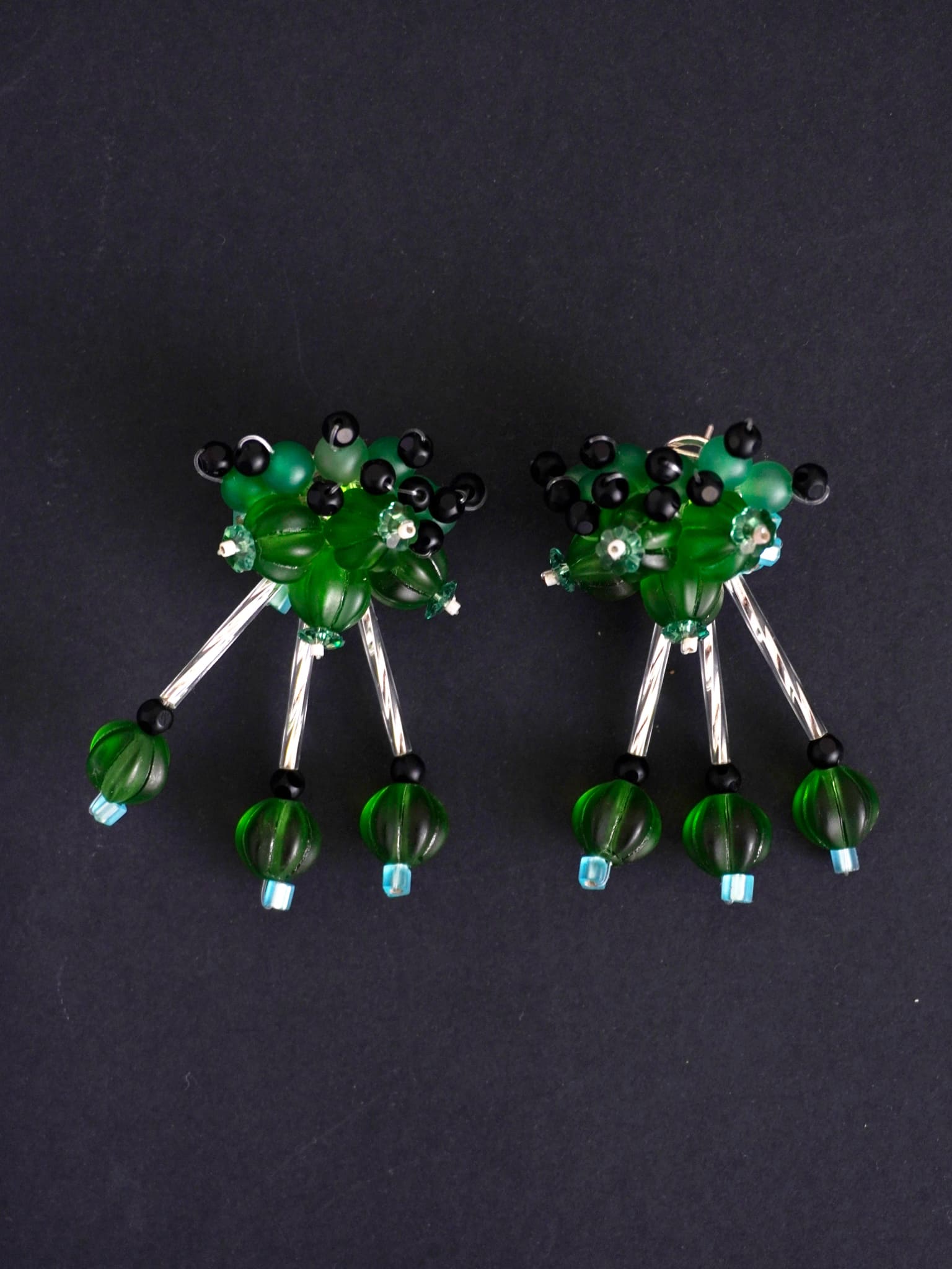 Pendientes bordados verde con diseño floral y cuentas de Murano, en fondo negro, marca Uchaworld.