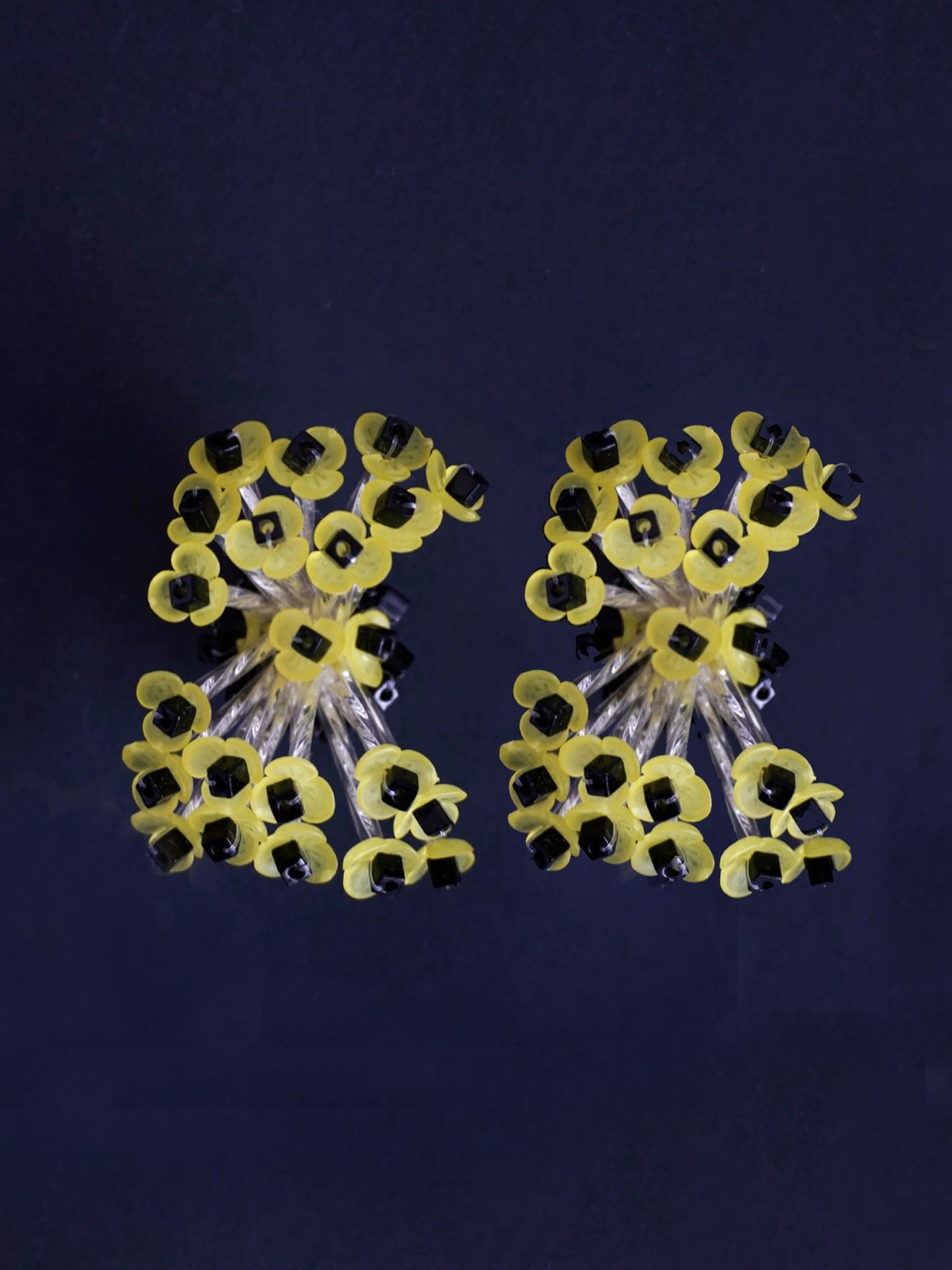 Pendientes bordados color amarillo y negro, con diseño floral y cuentas de acrilico y cristal, fondo negro, marca Uchaworld.